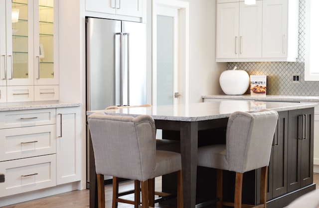 kitchen with white cupboards, dark wood island and 3 stools