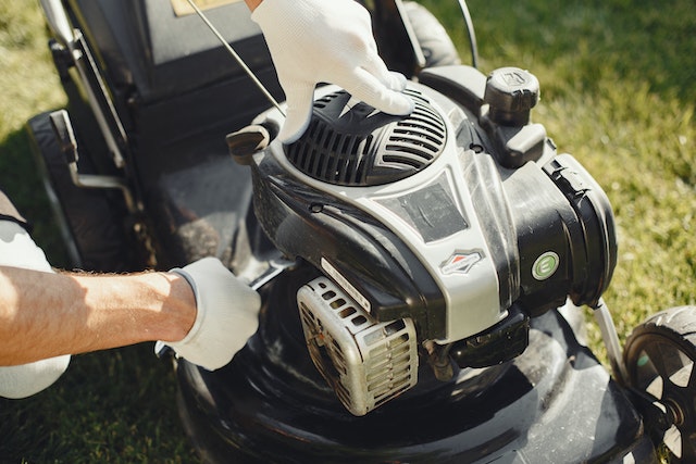person in white glovers fixing a lawn mower