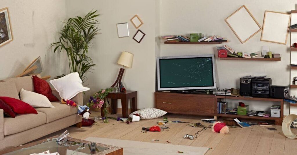 living room with broken lamps and tv and books fell off the shelf