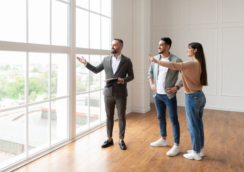 real estate agent show to people an unfurnished property with a view of the city