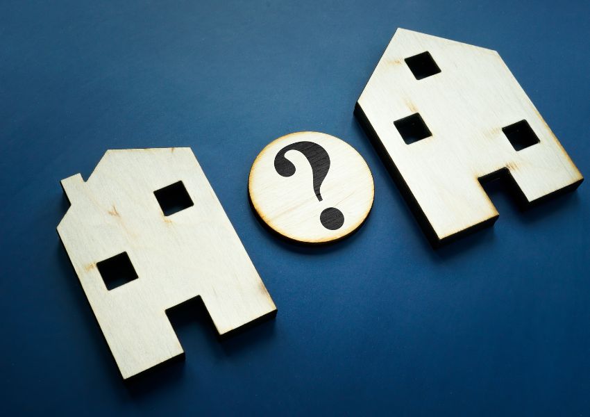 two home figurines with a question mark between them to symbolize a comparison