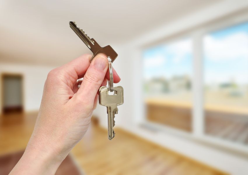 house keys being held up with an unfurnished room in the background