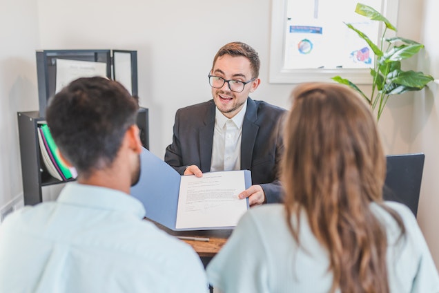 landlord showing two tenants a contract while sitting in their office