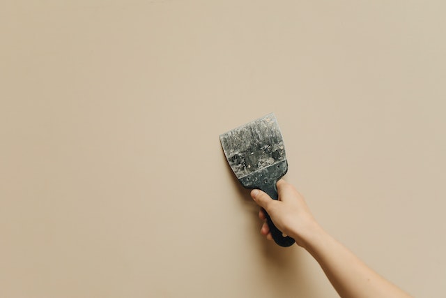 person using spackle to fix a small hole in the wall