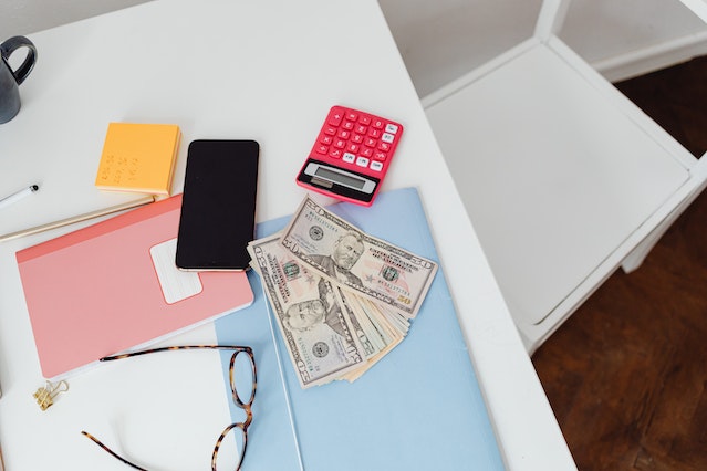 cash, different coloured folders and a calculator on a desk