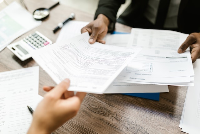 documents being exchanged between two people across a desk