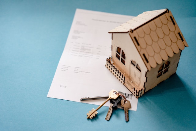 a house figurine and keys on top of a leasing document