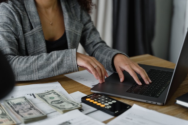 accountant counting cash and checking something on their laptop