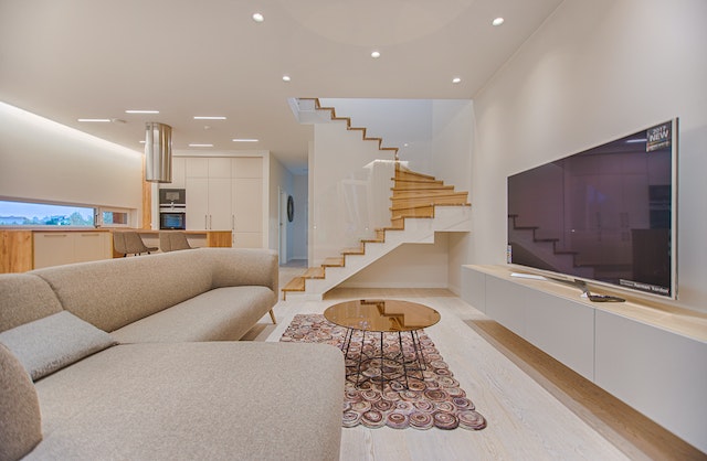 Minimalistic, decluttered living room, with white L-shaped sofa, a coffee table in center