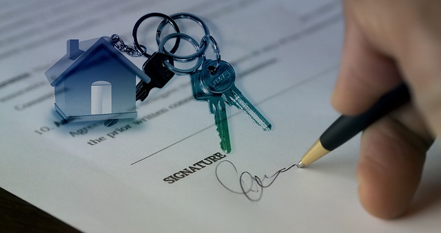 person-signing-a-sold-agreement-with-keys-on-i